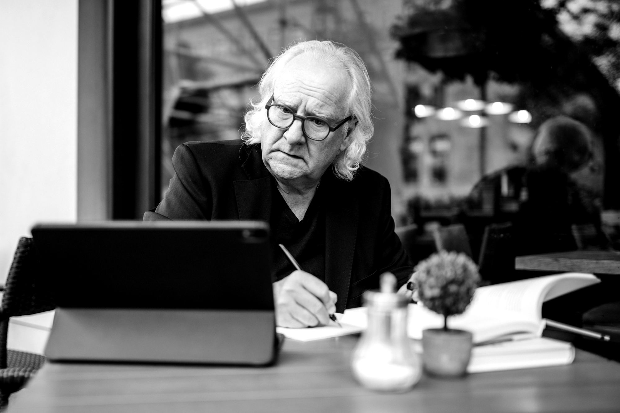 Brunello Gianella am Tisch, schreibend, vor ihm ein Tablet und Bücher