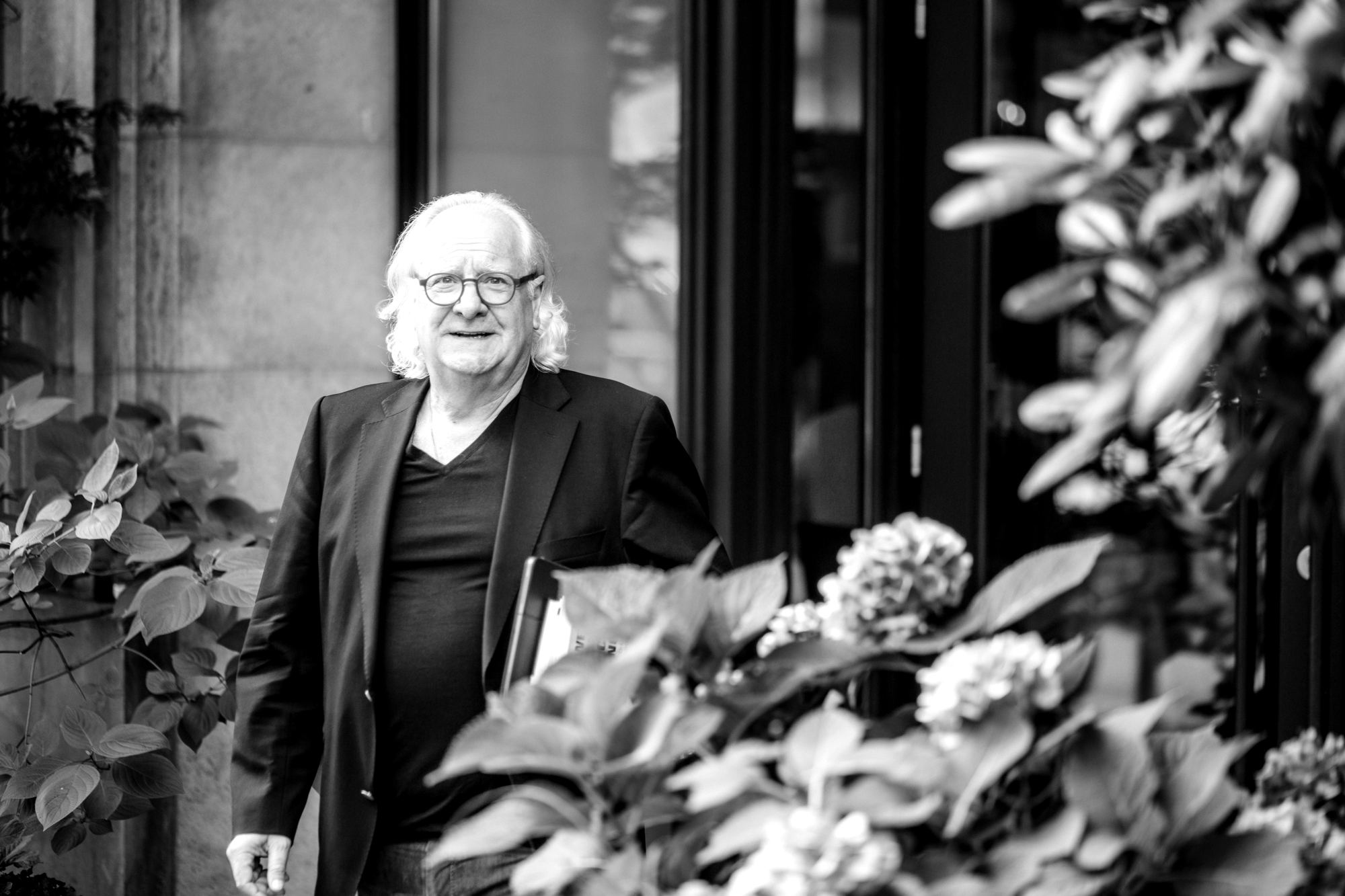 Brunello Gianella vor einem Hauseingang, im Vordergrund Hortensien